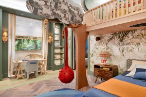 Vista geral do quarto infantil 'Pequena Amazônia' na CASACOR, destacando a árvore cenográfica e o papel de parede temático.